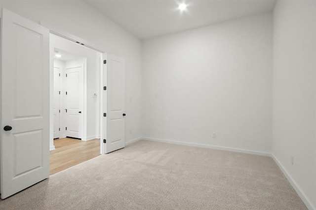 unfurnished room with light carpet and baseboards