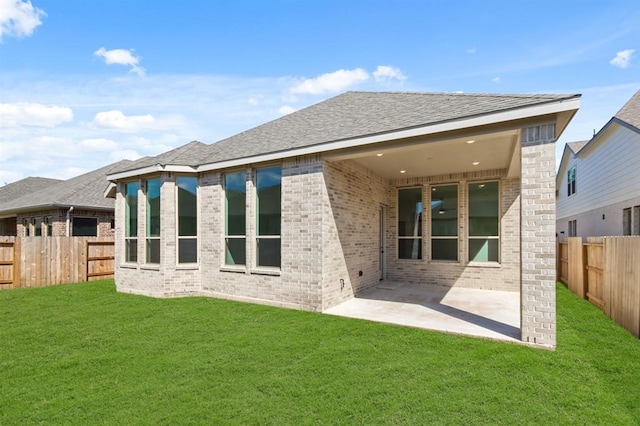 rear view of house with a patio, a yard, a fenced backyard, and brick siding