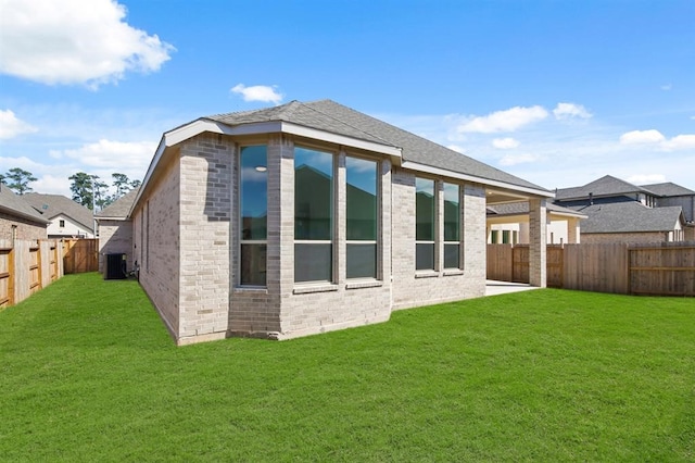 rear view of house with a lawn, cooling unit, and a fenced backyard