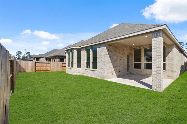 rear view of house featuring a patio, a yard, a fenced backyard, and brick siding