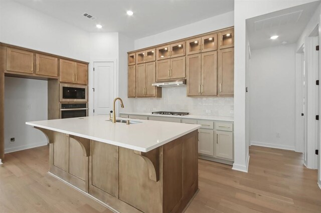 kitchen with stainless steel appliances, light wood-style floors, brown cabinets, a sink, and visible vents