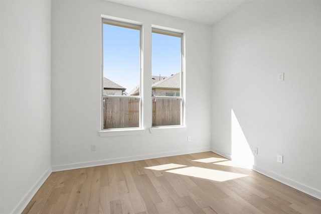 spare room featuring baseboards and wood finished floors
