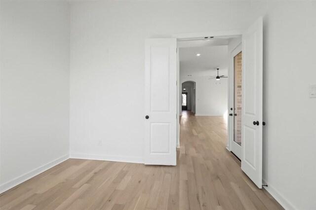 interior space with arched walkways, baseboards, and light wood-type flooring