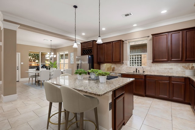 kitchen with a center island, stainless steel fridge with ice dispenser, light stone counters, backsplash, and pendant lighting