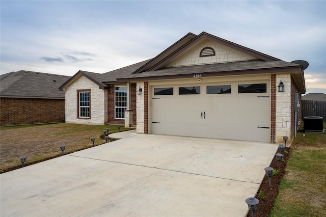 single story home featuring cooling unit, a garage, and a front lawn