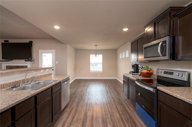 kitchen featuring pendant lighting, sink, appliances with stainless steel finishes, dark hardwood / wood-style flooring, and dark brown cabinetry