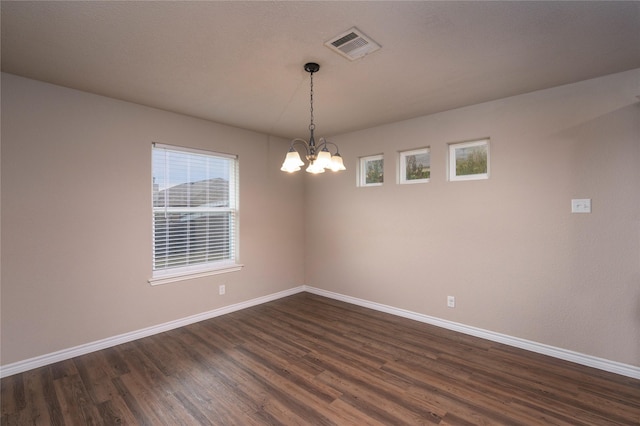 unfurnished room with a chandelier and dark hardwood / wood-style floors