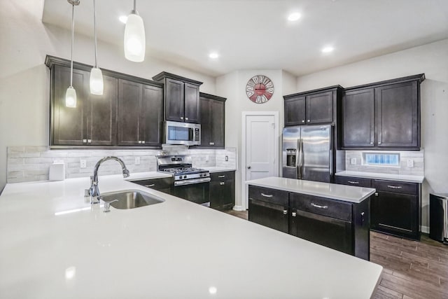 kitchen with sink, hanging light fixtures, dark hardwood / wood-style floors, decorative backsplash, and appliances with stainless steel finishes