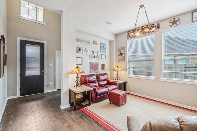 living room with plenty of natural light, dark hardwood / wood-style floors, and a notable chandelier