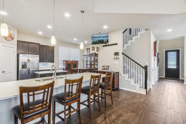 kitchen featuring dark hardwood / wood-style flooring, dark brown cabinets, sink, pendant lighting, and stainless steel fridge with ice dispenser