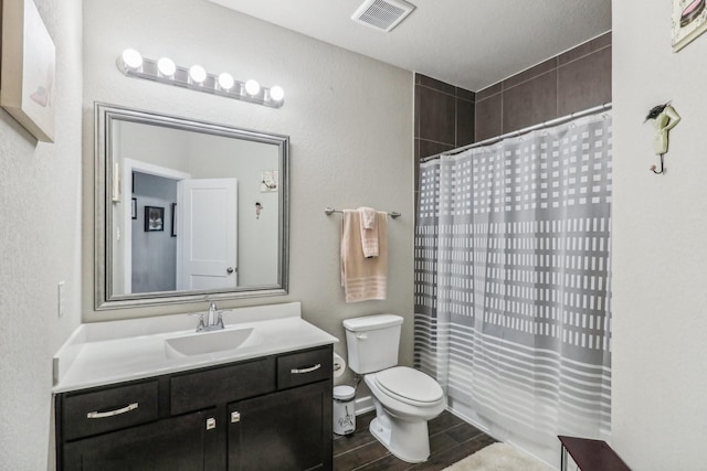 bathroom with hardwood / wood-style floors, a textured ceiling, toilet, vanity, and a shower with shower curtain