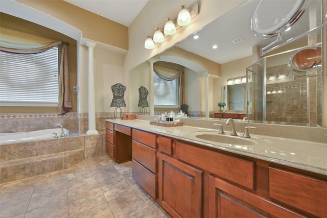 bathroom with tile patterned flooring, vanity, ornate columns, and tiled tub