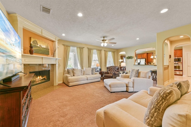 carpeted living room featuring ceiling fan, a textured ceiling, and a high end fireplace