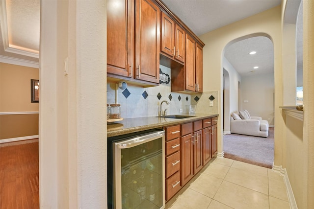 kitchen with backsplash, crown molding, sink, wine cooler, and light tile patterned floors