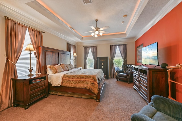 bedroom featuring ceiling fan, crown molding, a textured ceiling, a tray ceiling, and light carpet