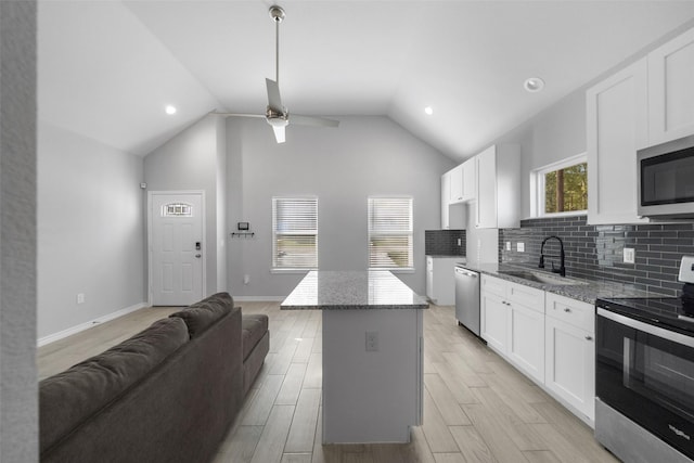 kitchen featuring white cabinets, a center island, stainless steel appliances, and sink