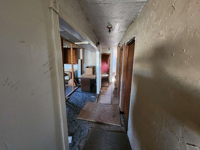 corridor with a barn door and a textured ceiling