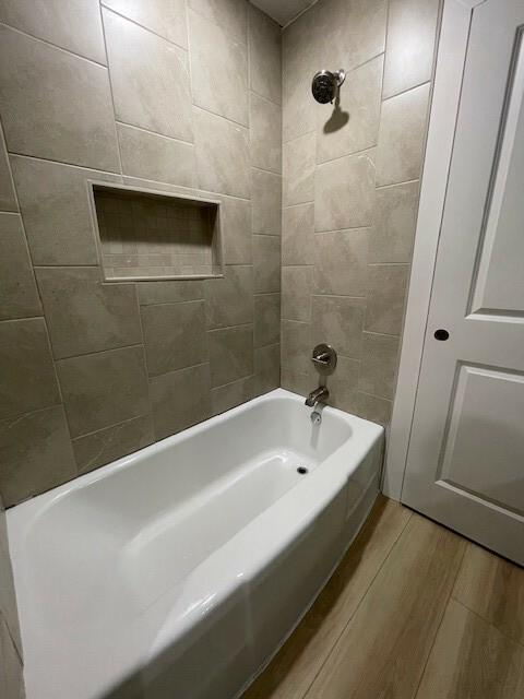 bathroom with hardwood / wood-style floors and tiled shower / bath