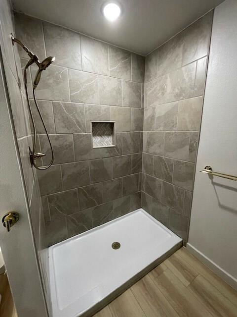 bathroom with hardwood / wood-style floors and a tile shower