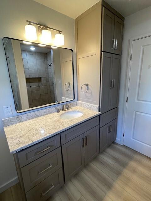 bathroom with a tile shower, hardwood / wood-style floors, and vanity