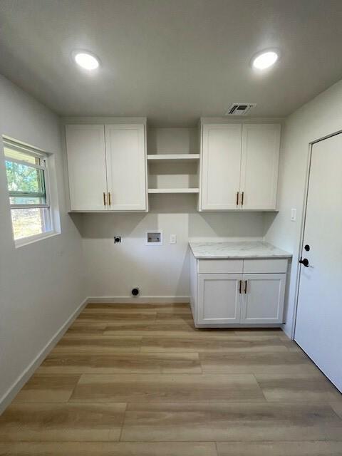 clothes washing area featuring cabinets, light hardwood / wood-style floors, and washer hookup