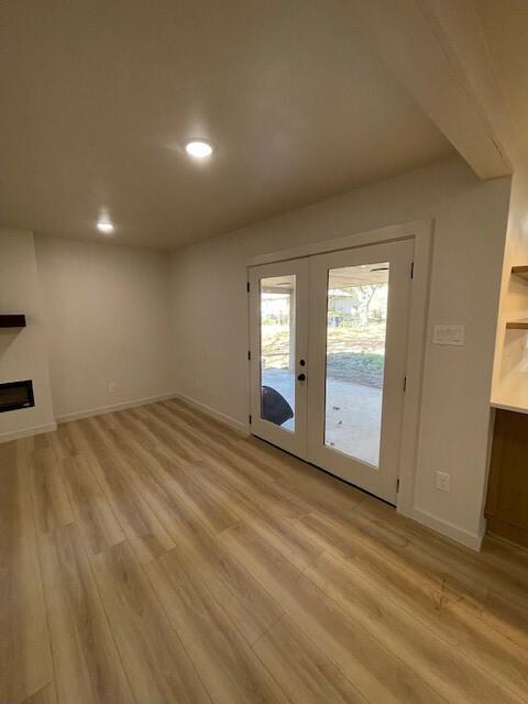 unfurnished living room featuring light wood-type flooring and french doors