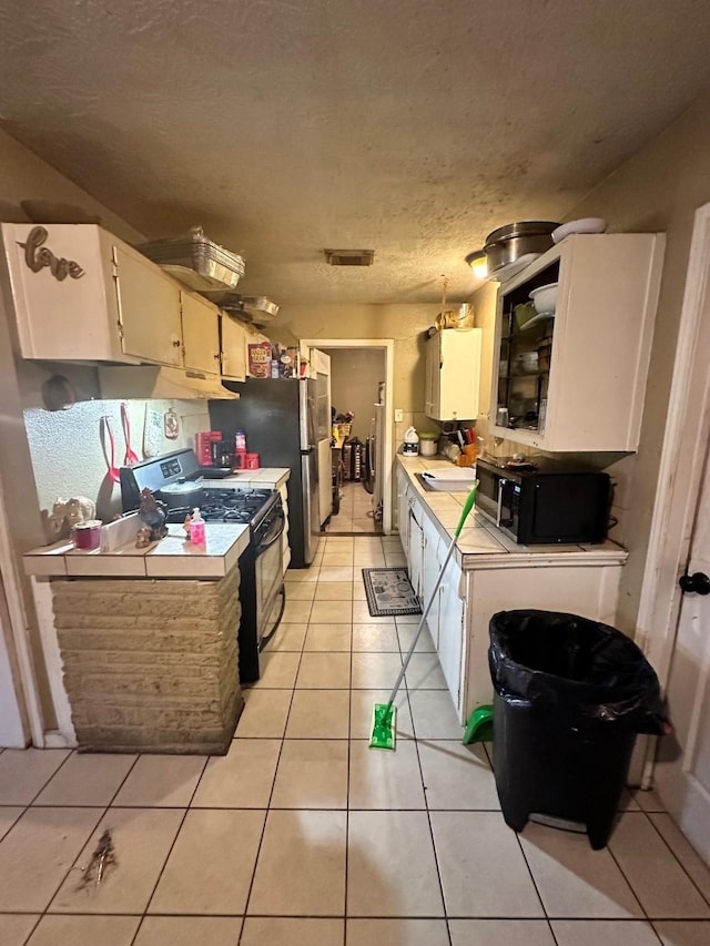 kitchen featuring sink, black appliances, decorative light fixtures, white cabinetry, and light tile patterned flooring