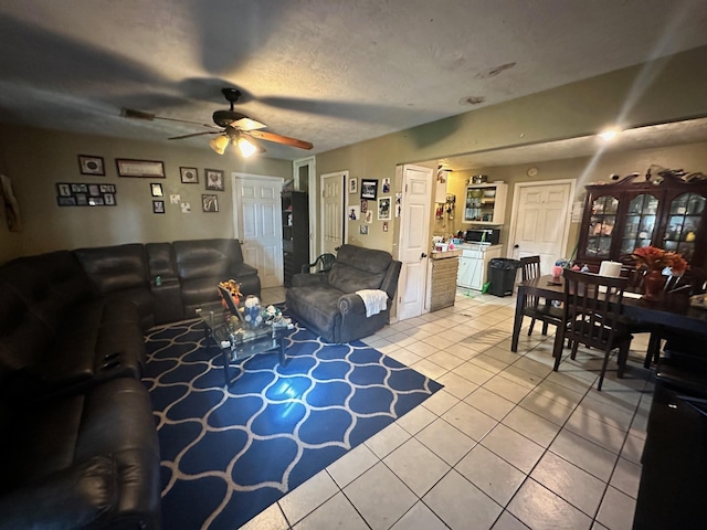 living room featuring ceiling fan, light tile patterned floors, and a textured ceiling