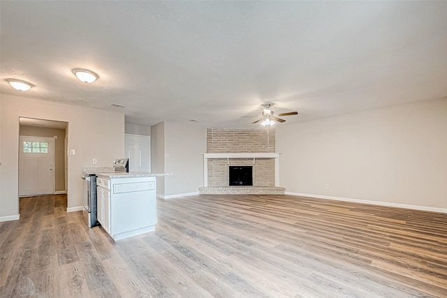 unfurnished living room featuring a fireplace, light wood-type flooring, and ceiling fan