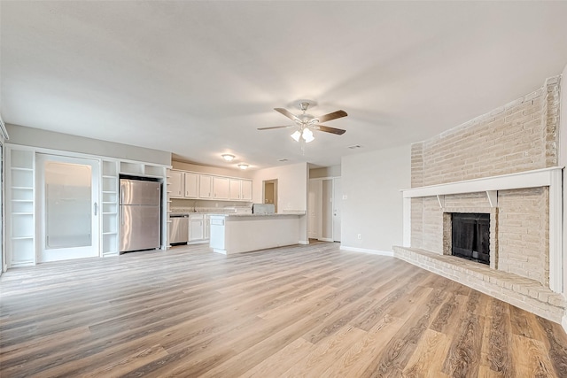 unfurnished living room with ceiling fan, light hardwood / wood-style floors, and a brick fireplace