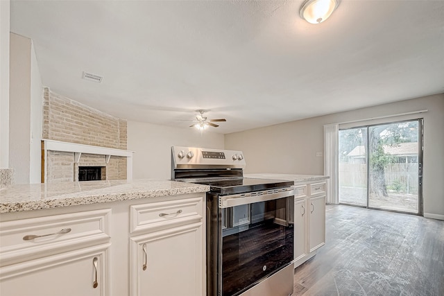 kitchen featuring a fireplace, ceiling fan, light hardwood / wood-style flooring, white cabinets, and stainless steel electric range