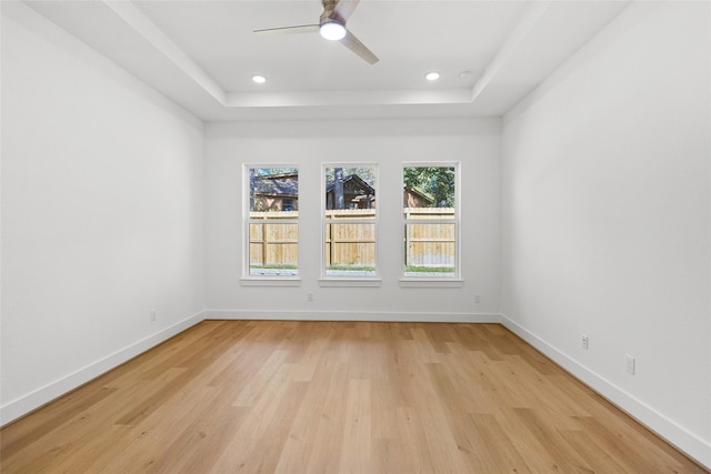 unfurnished room with a tray ceiling, ceiling fan, and light hardwood / wood-style flooring