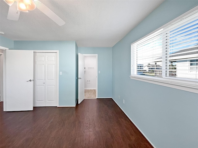 unfurnished bedroom featuring dark hardwood / wood-style flooring, a textured ceiling, a closet, and ceiling fan