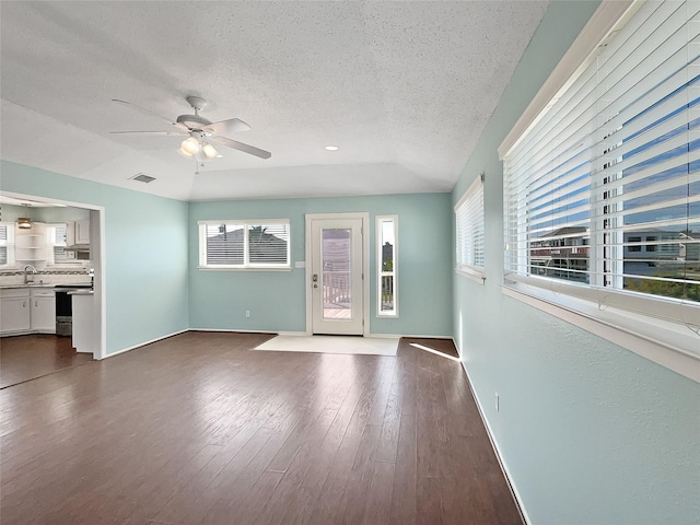 unfurnished living room featuring a textured ceiling, dark hardwood / wood-style floors, ceiling fan, and sink