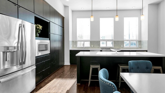 kitchen featuring hanging light fixtures, stainless steel appliances, dark hardwood / wood-style floors, a breakfast bar area, and a kitchen island