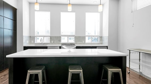 kitchen with wood-type flooring, a center island, decorative light fixtures, and backsplash