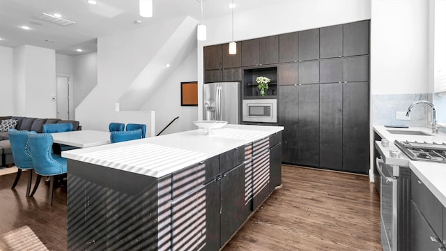 kitchen featuring appliances with stainless steel finishes, dark wood-type flooring, pendant lighting, and sink