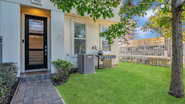 view of exterior entry with a lawn and central air condition unit