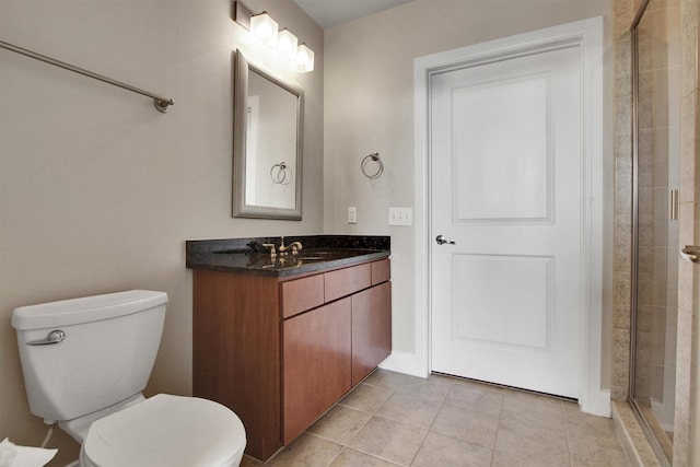 bathroom featuring tile patterned floors, vanity, toilet, and a shower with door