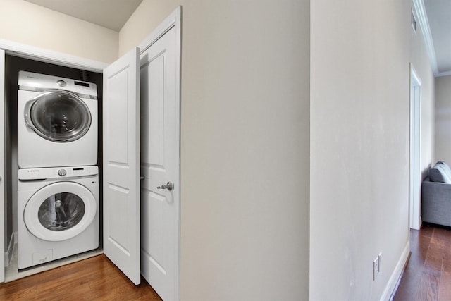 laundry room featuring dark wood-type flooring and stacked washing maching and dryer