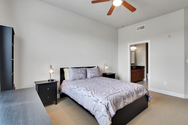 carpeted bedroom with ensuite bath and ceiling fan