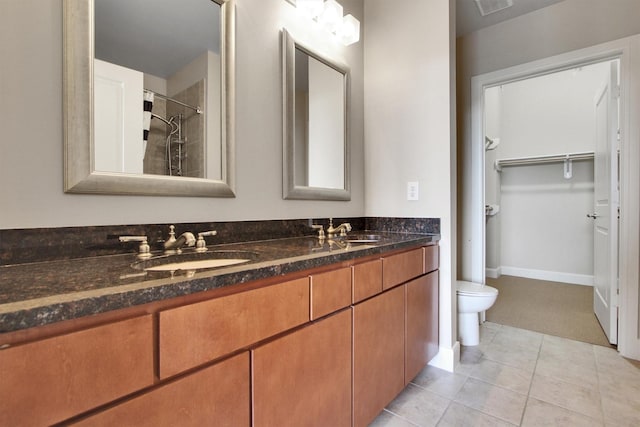 bathroom with tile patterned flooring, vanity, toilet, and tiled shower