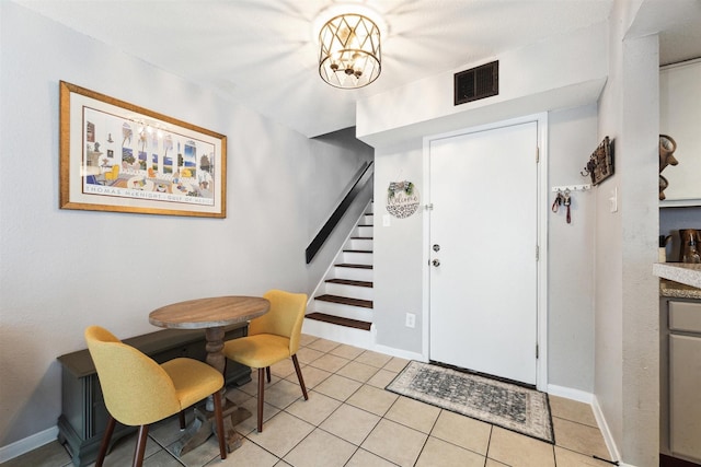 tiled foyer entrance with a notable chandelier