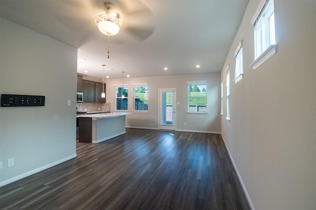 unfurnished living room with dark hardwood / wood-style flooring and ceiling fan