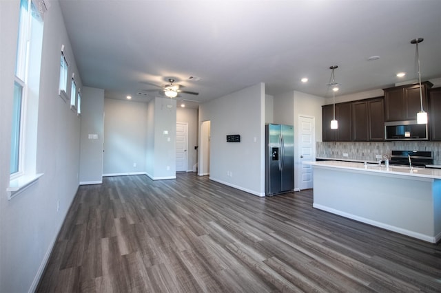 kitchen with appliances with stainless steel finishes, dark hardwood / wood-style flooring, dark brown cabinets, and backsplash