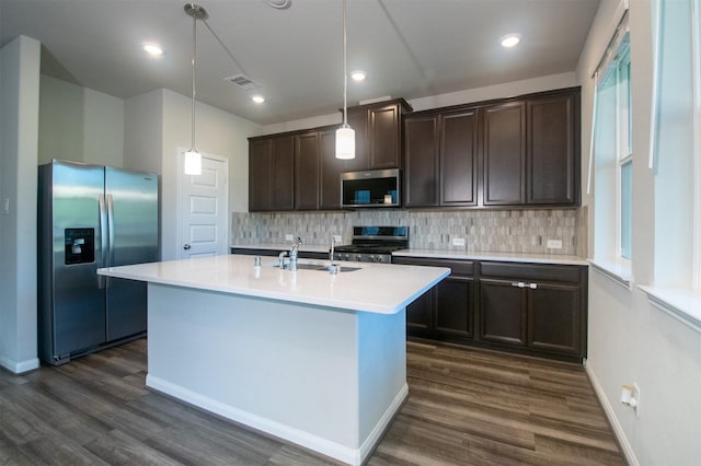 kitchen with pendant lighting, a center island with sink, sink, dark hardwood / wood-style flooring, and stainless steel appliances