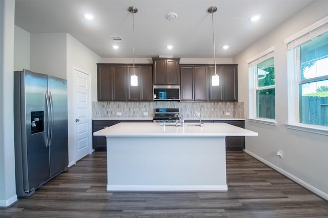 kitchen featuring stainless steel appliances, hanging light fixtures, and dark wood-type flooring