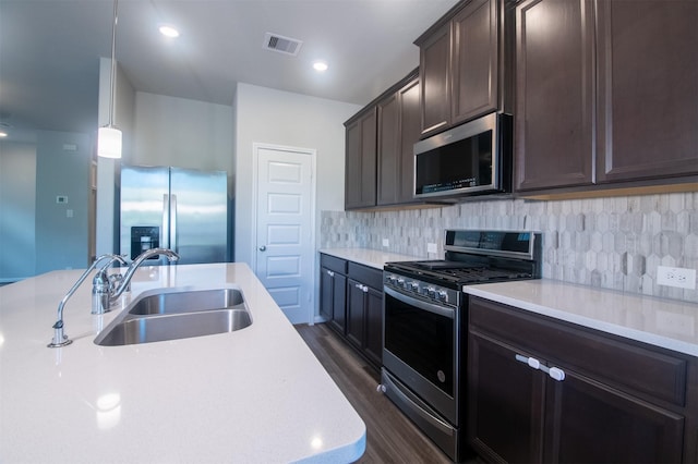 kitchen with sink, tasteful backsplash, dark hardwood / wood-style floors, pendant lighting, and appliances with stainless steel finishes