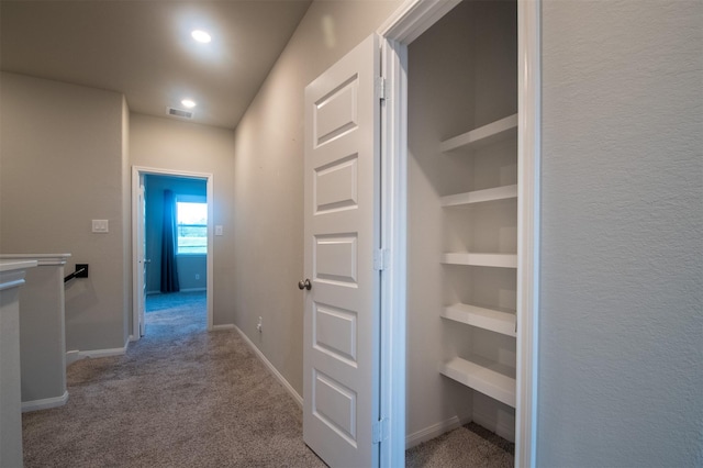 hallway featuring light carpet and built in shelves