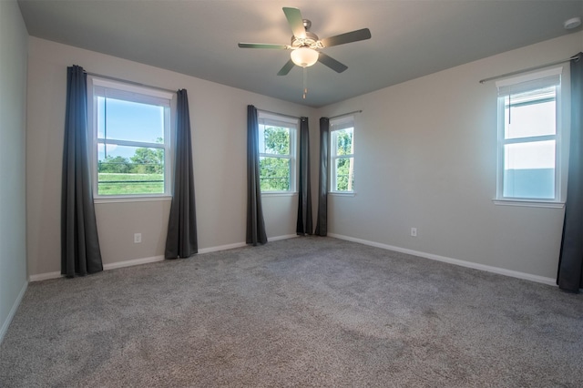 carpeted empty room with a wealth of natural light and ceiling fan